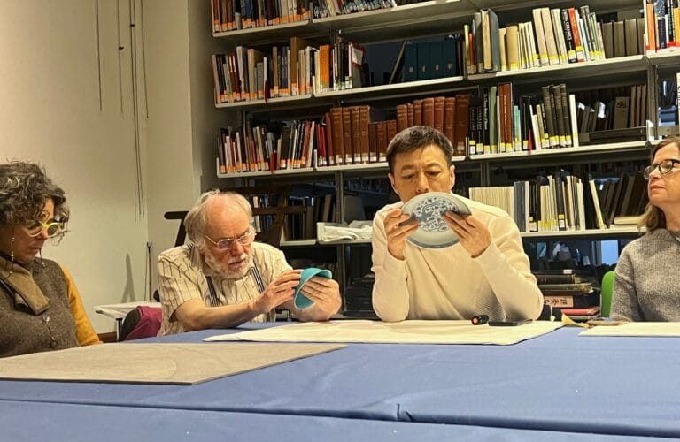 four members seated around a table, handling and inspecting Chinese ceramics at the British Museum
