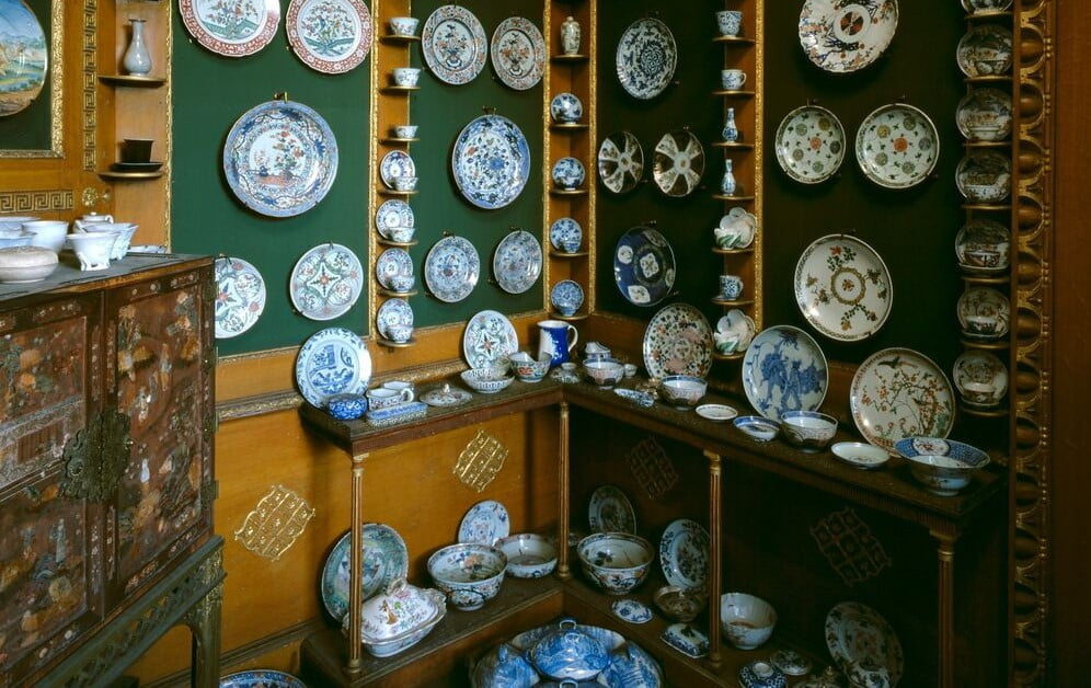 Corner of a room in a property belonging to the National Trust for Scotland showing many bowls, dishes and vases covering the walls and surfaces of furniture
